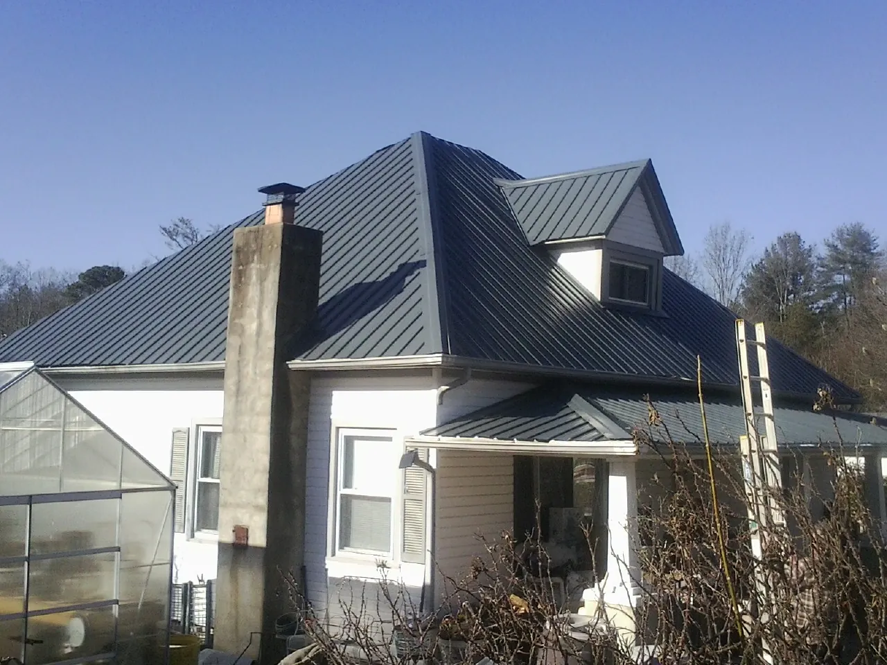 Dark blue standing seam metal roof on a white farmhouse with dormer — Slate & Tile Roof Repair by Roofing Brothers in Orangeville