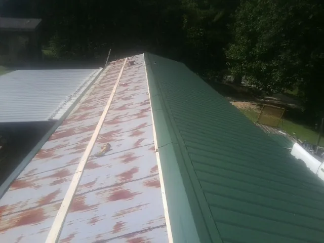 Old rusted panels beside newly installed green metal roofing — Wind Damage Roof Repair by Roofing Brothers in Orangeville