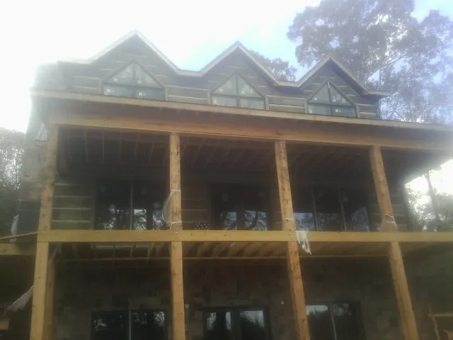 Dormers and porch framing on a large log home under construction — Roof Coating work by our crew in Orangeville