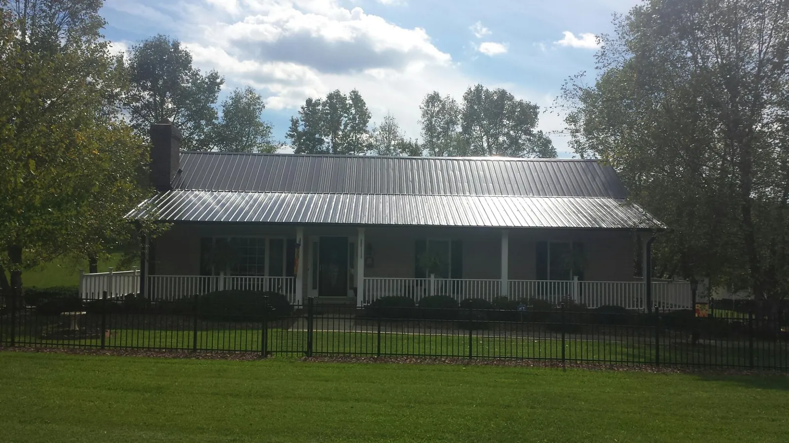 Gray metal roof on a brick ranch with a full width front porch — Gutter Guard Installation work by our crew in Orangeville
