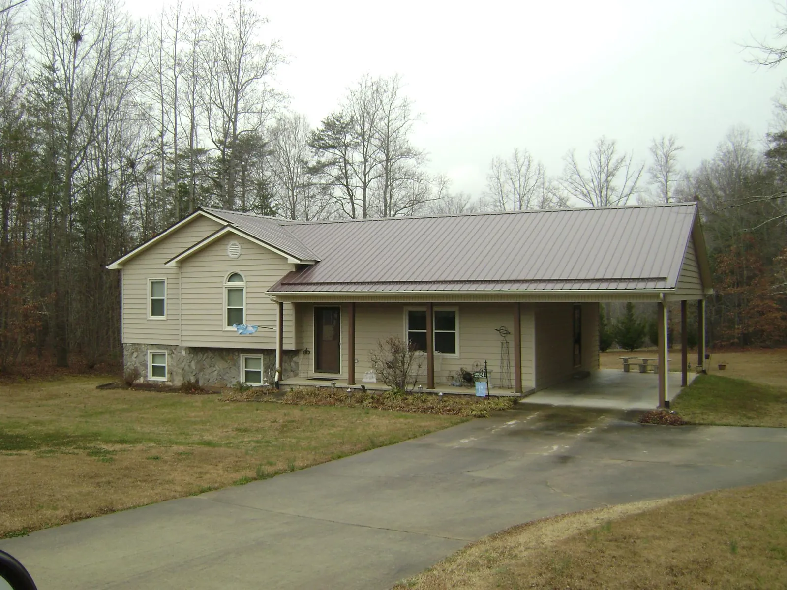 Brown metal roof on a tan split level home with an attached carport in Orangeville