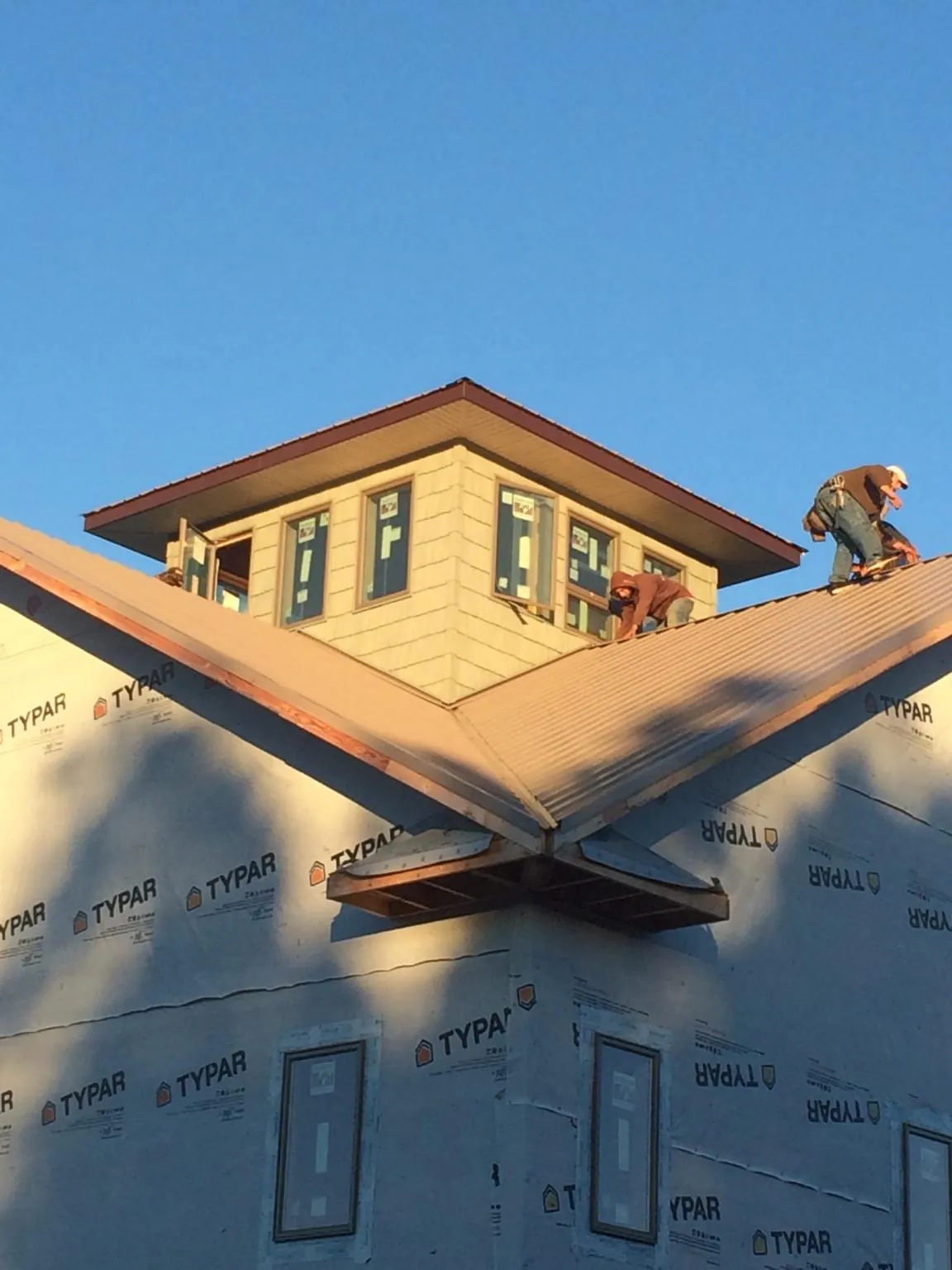 Roofers working around a rooftop cupola on a new metal roof at sunset — Roof Waterproofing in Orangeville by Roofing Brothers
